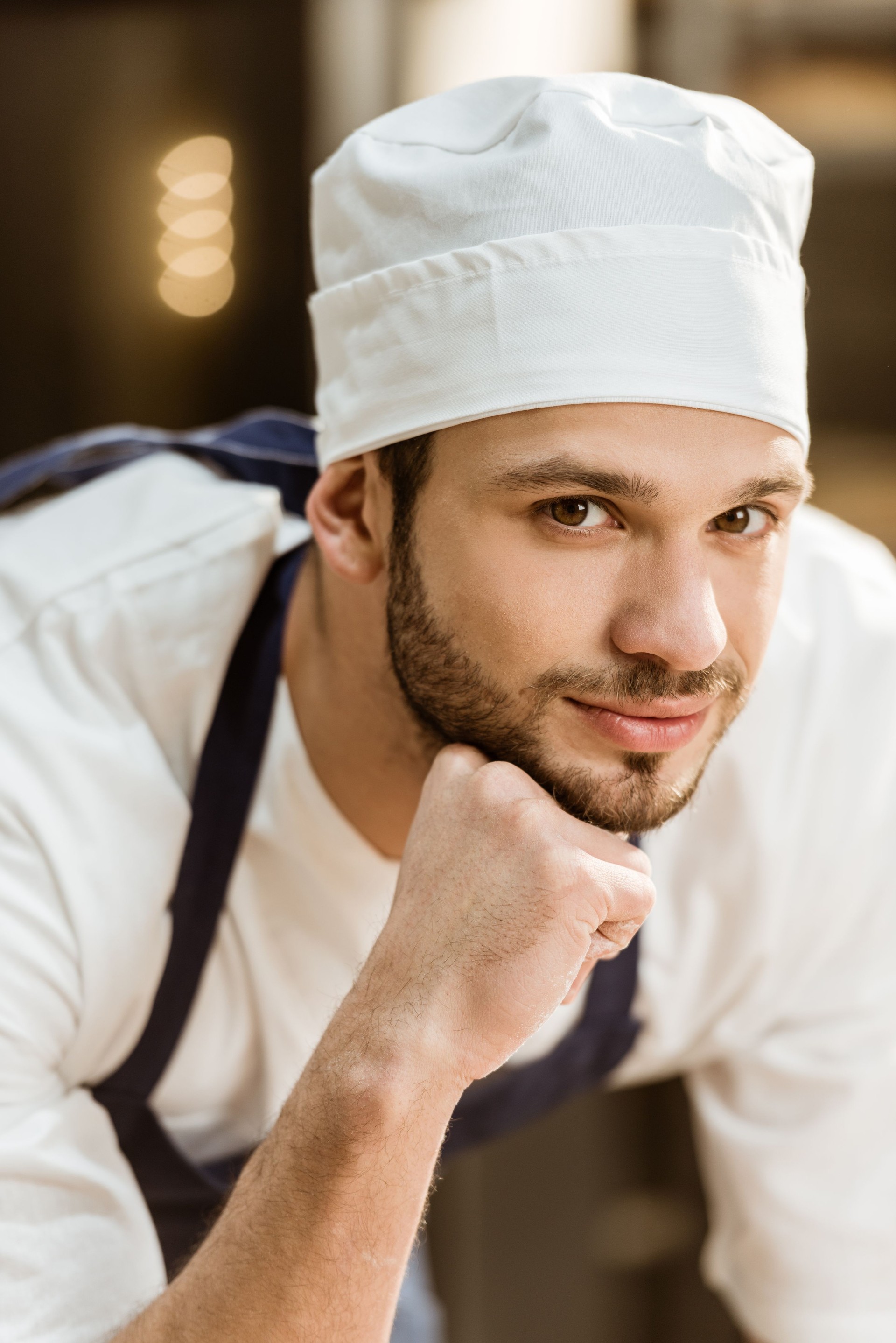 close-up portrait of handsome young baker looking at camera on baking manufacture